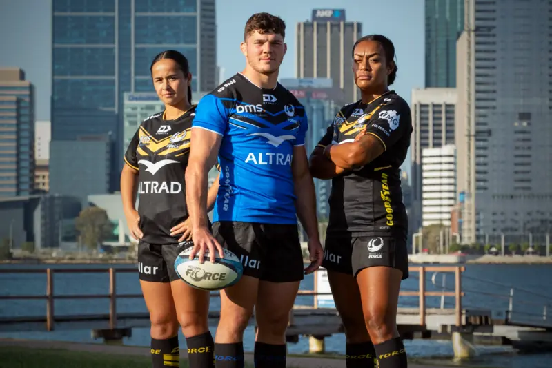 1 male and 2 female wearing custom rugby uniform in blue and black colors buildings in background