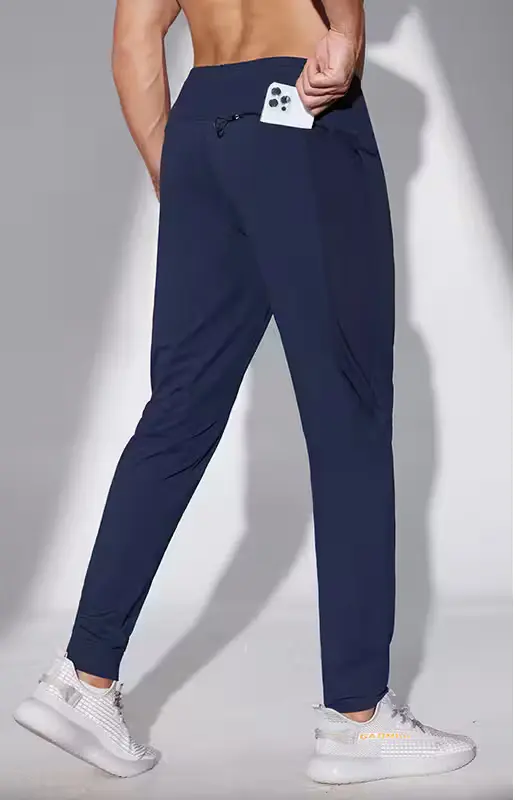 male posing in blue stretchable sweatpants holding phone in back pocket. designed by sweatpants manufacturers