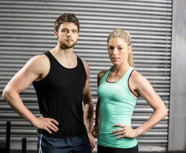 Fitness couple posing in gym attire Wearing Custom tank tops.